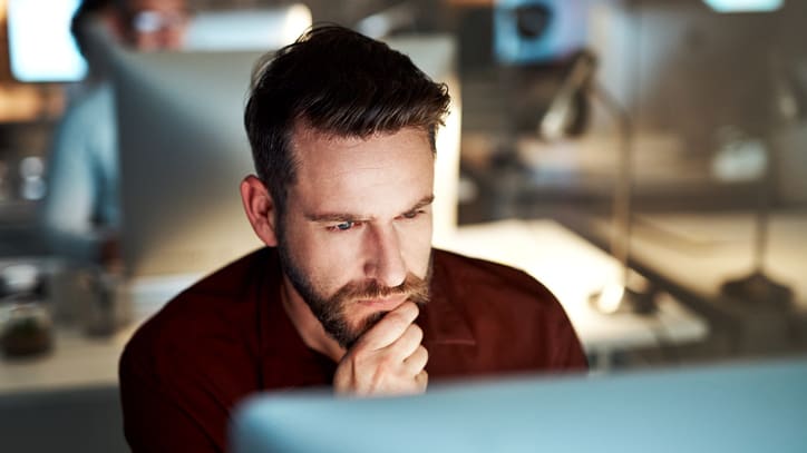 A man is sitting in front of a computer screen.