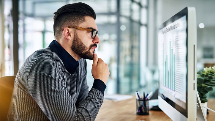 A man looking at a graph on a computer screen.