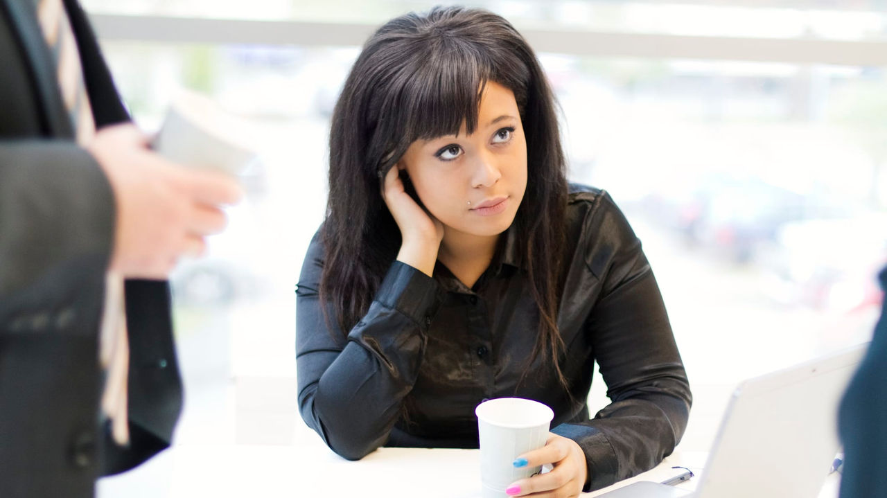 A woman sitting at a desk with a laptop and a cup of coffee.