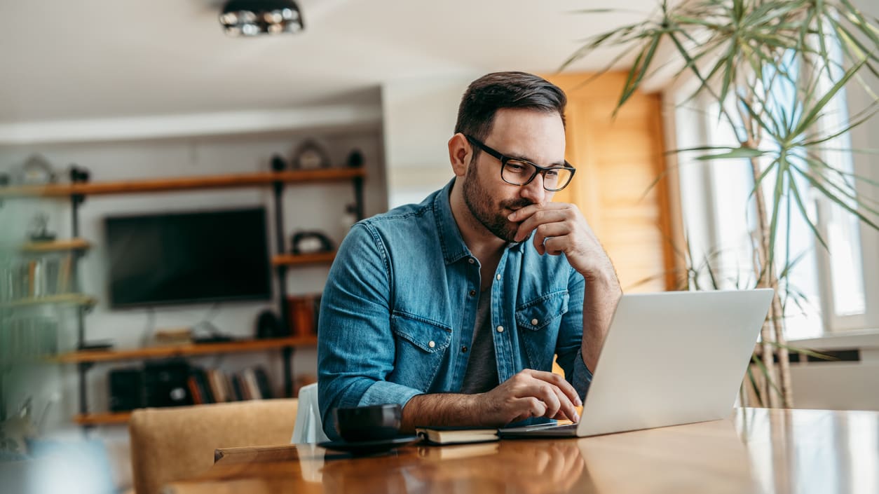 A man sitting at a table using a laptop.