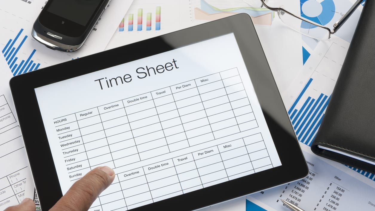 A person holding a tablet with a time sheet on it.