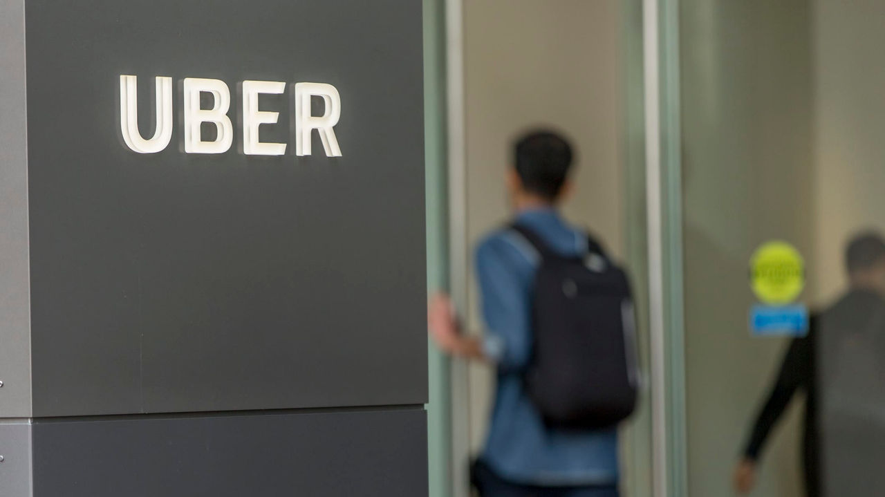 A sign with the word uber on it in front of a building.