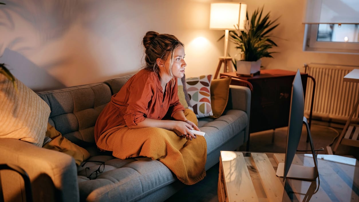 A woman sitting on a couch watching tv.