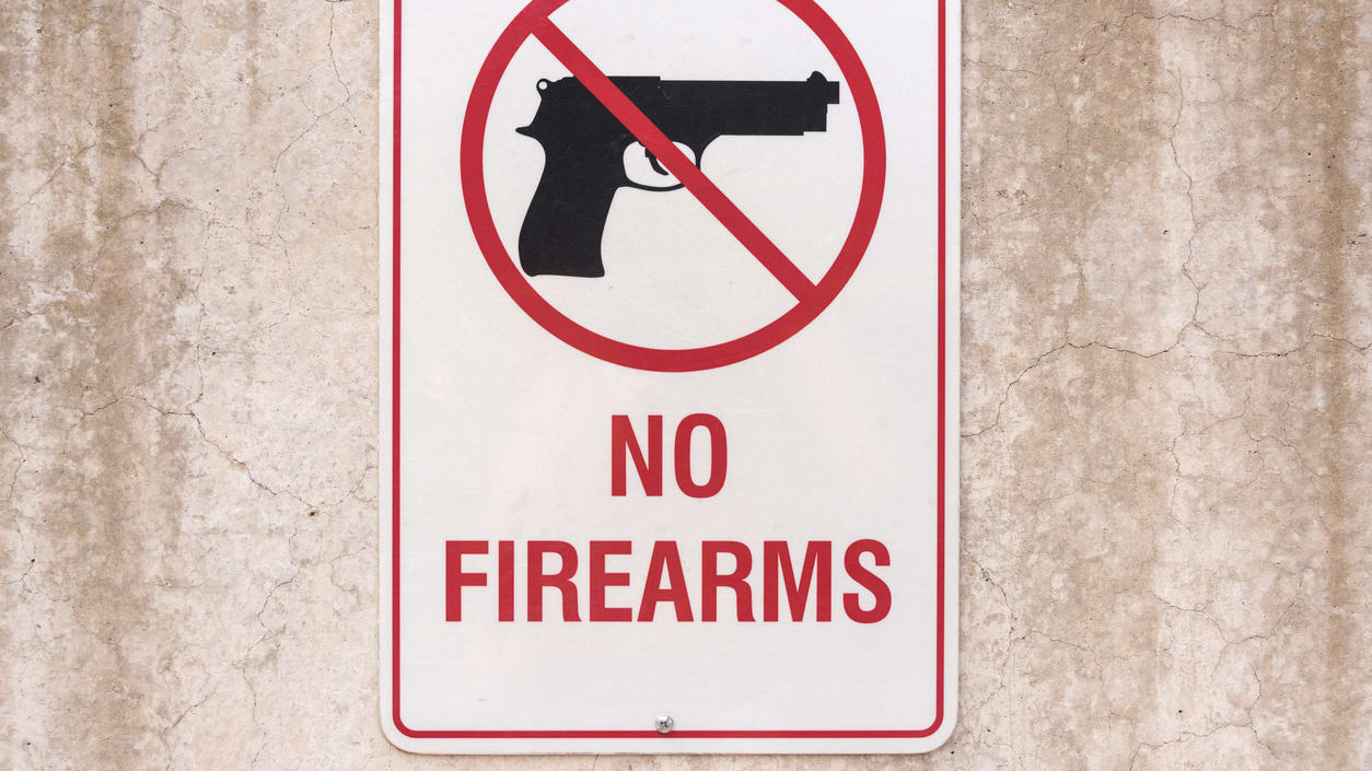 No firearms sign on a concrete wall.