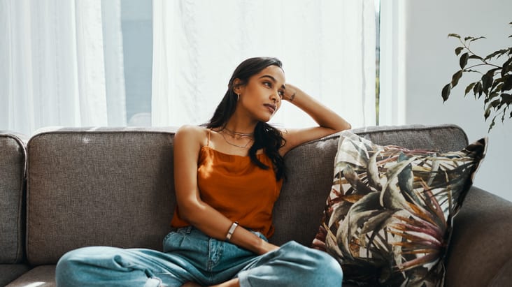 A woman sitting on a couch in front of a window.