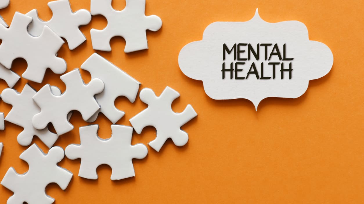 Mental health puzzle pieces on an orange background.