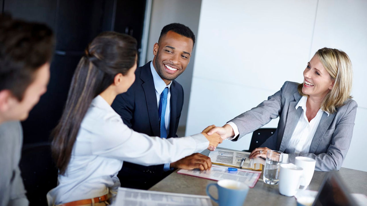 A group of business people shaking hands at a meeting.