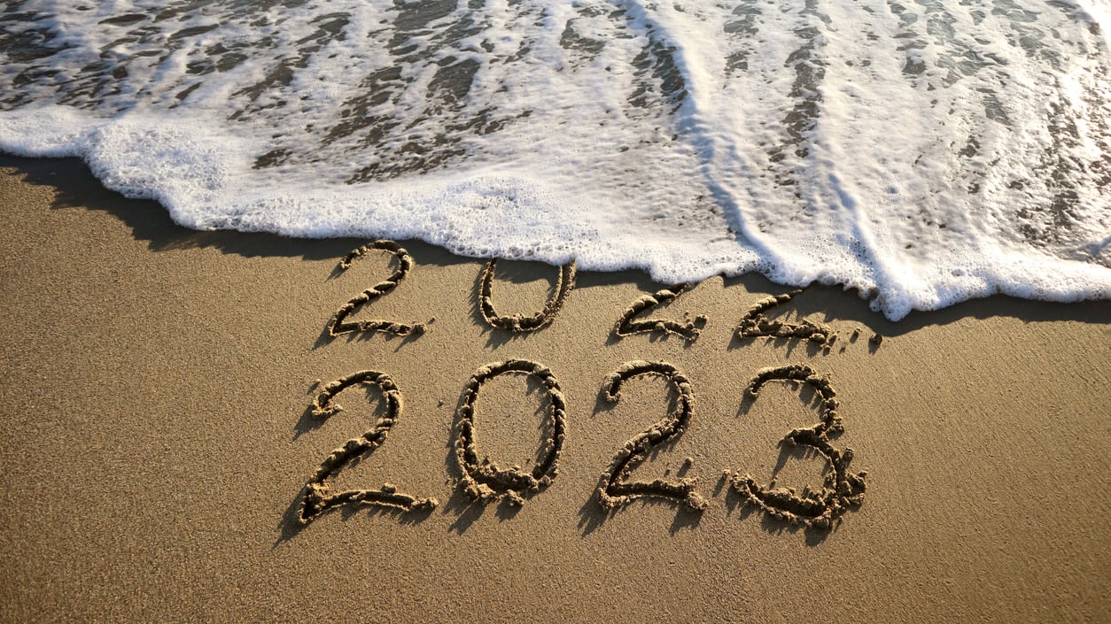 The numbers 2020 written in the sand on a beach.