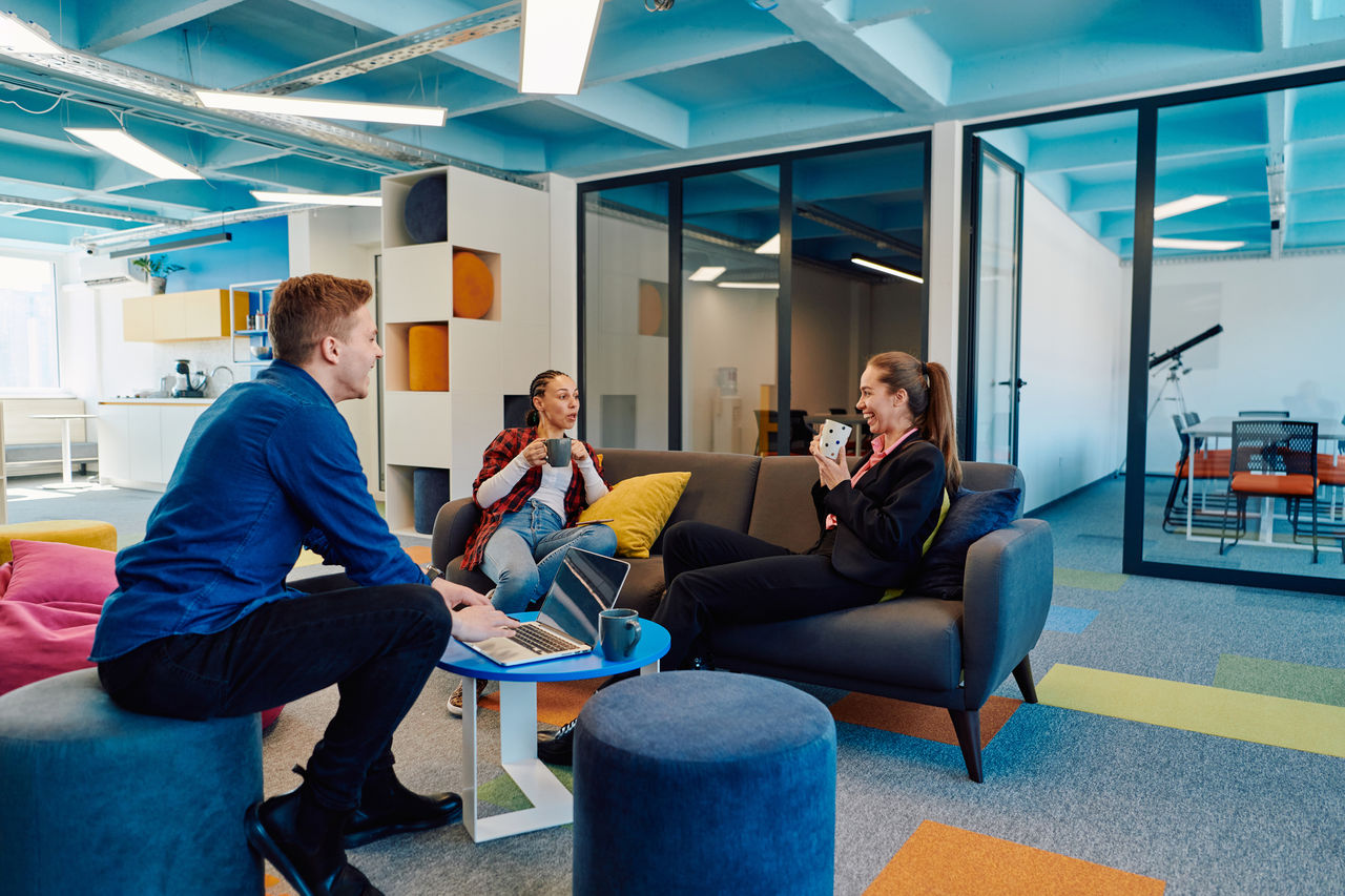Multiethnic startup business team on meeting in a modern bright open space coworking office. Brainstorming, working on laptop. Group of coworkers walking around in motion blur.