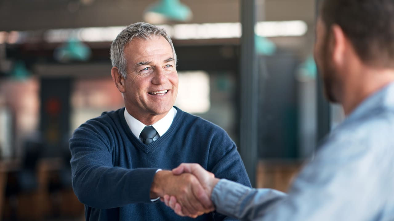 A man shaking hands with another man in an office.