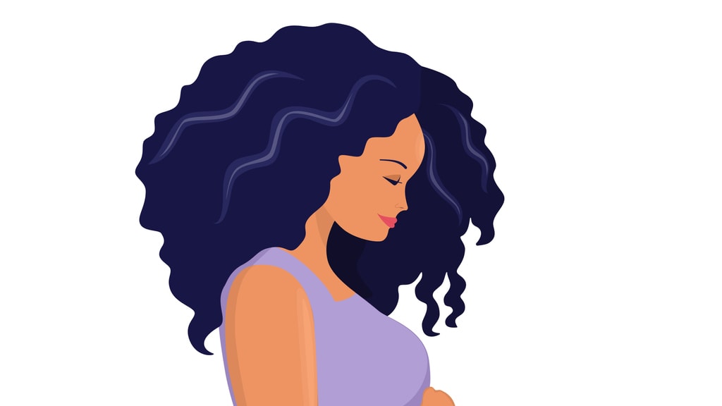 A pregnant woman with curly hair is holding her stomach.