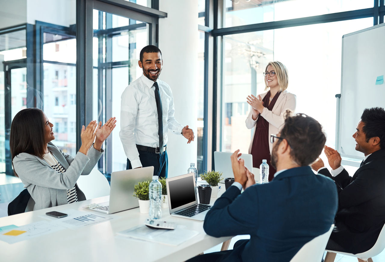 Shot of businesspeople applauding a colleague in an office
