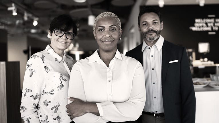 Three business people posing for a photo in an office.