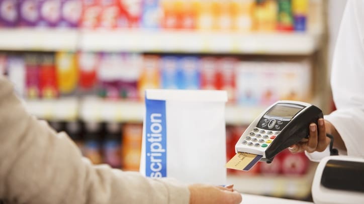 A pharmacist is handing over a credit card to a customer.