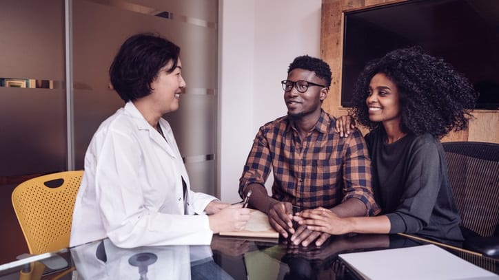 Three people sitting at a table talking to a doctor.