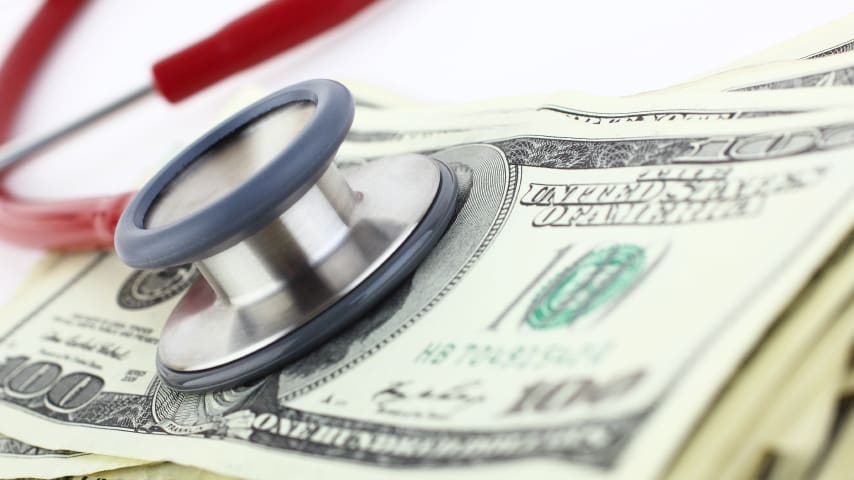 A stethoscope sits on top of a stack of money.