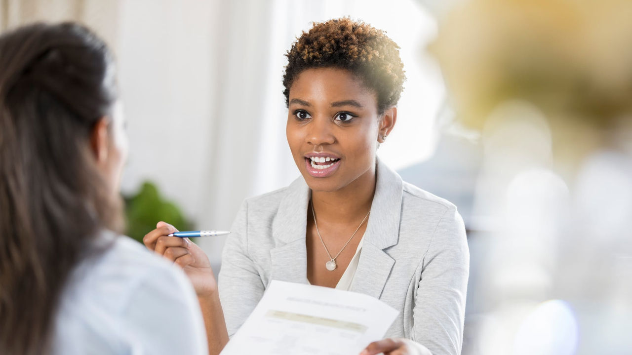 A woman is talking to another woman in an office.