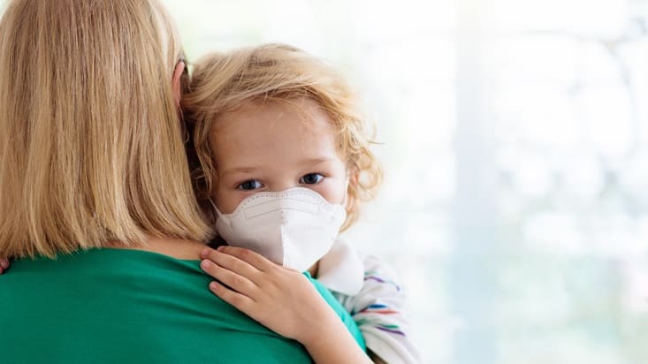 A woman wearing a face mask with a child.