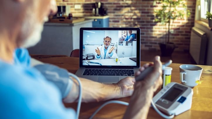 A man is using a laptop to monitor his blood pressure.