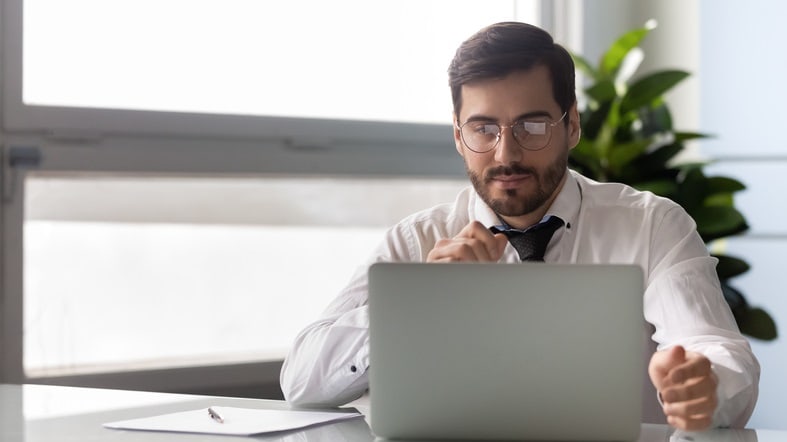 A man sitting at a desk using a laptop.