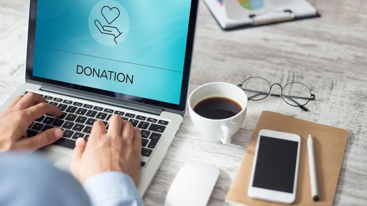 A man using a laptop with the word donation on it.