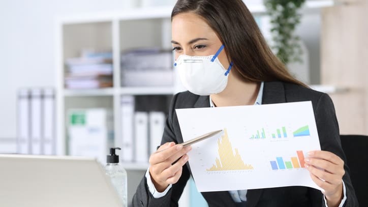 A business woman wearing a face mask while working at her computer.