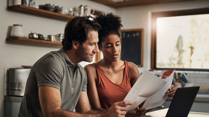 A couple looking at a document on a laptop.