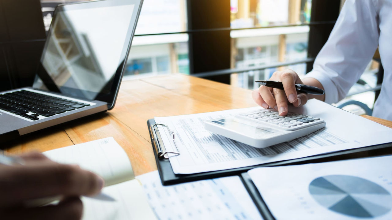 A man and woman working on a spreadsheet at a desk.