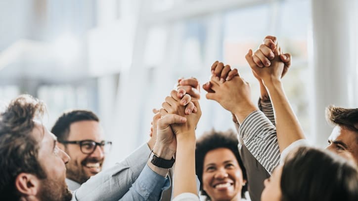 A group of business people raising their hands in the air.