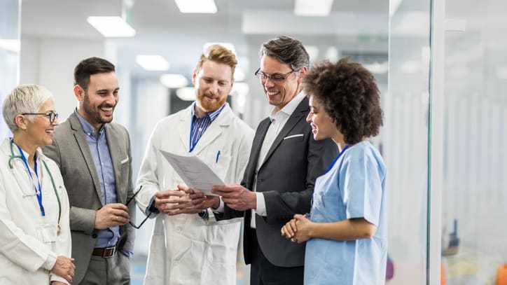 A group of doctors and nurses talking in a hospital hallway.