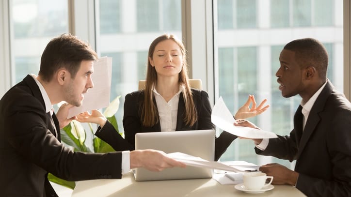 A group of business people sitting around a table in an office.