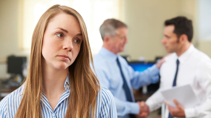 A woman is standing in front of a group of people in an office.