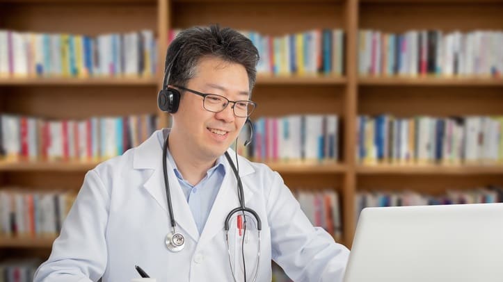 A doctor using a laptop in a library.