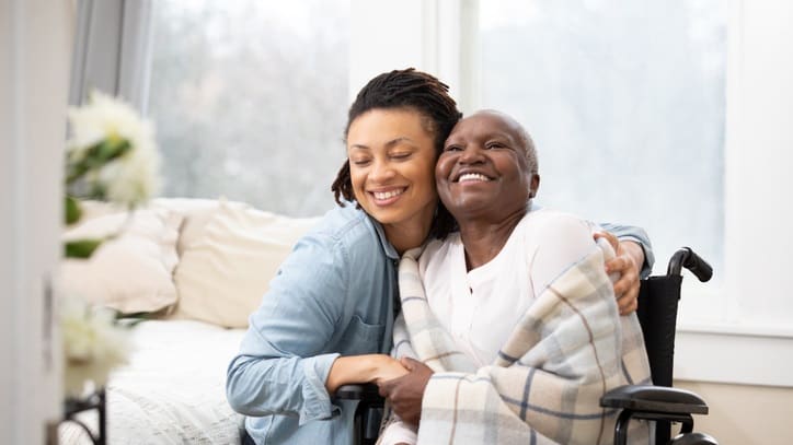 A woman in a wheelchair is hugging another woman.