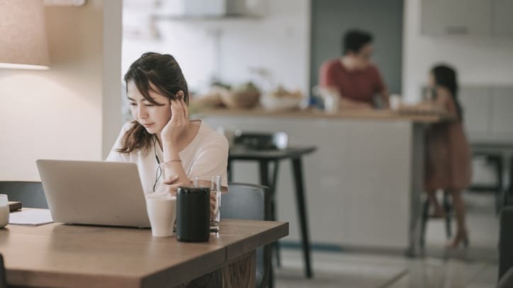 A woman is sitting at a table working on her laptop.