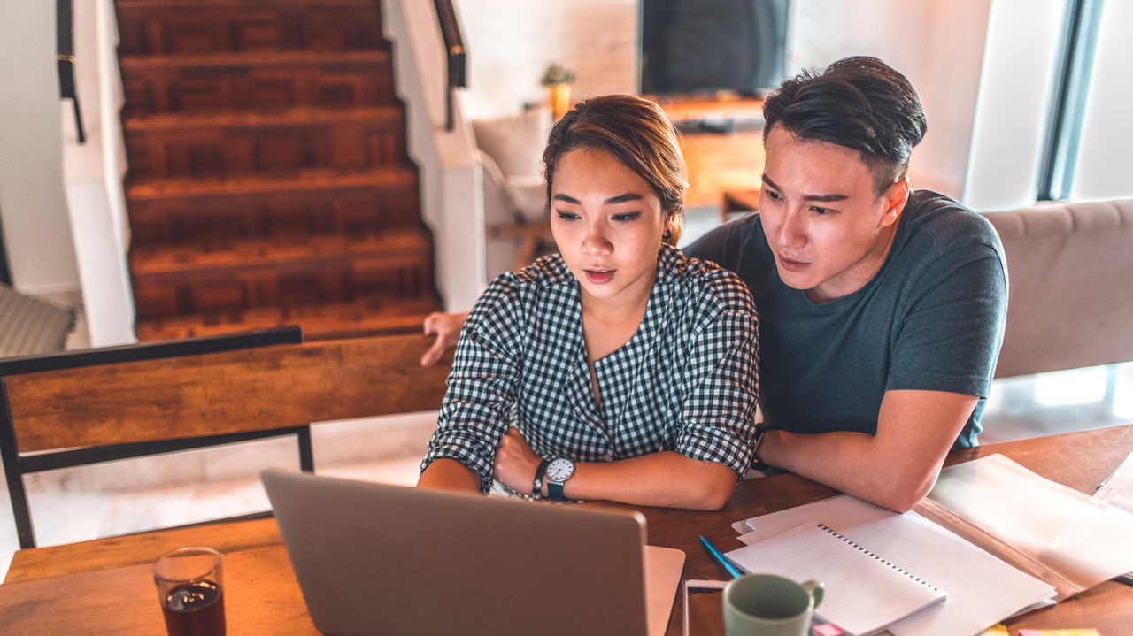 A man and woman looking at a laptop at a table.