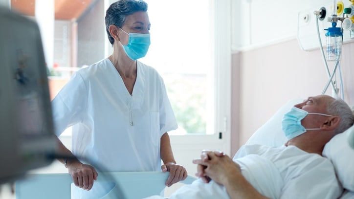 A nurse is standing next to a patient in a hospital bed.