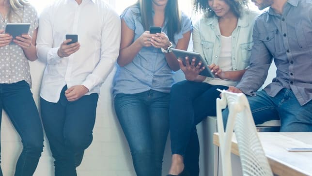 A group of people looking at their cell phones.