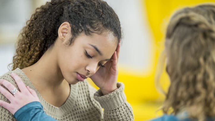 A girl is talking to another girl in a classroom.