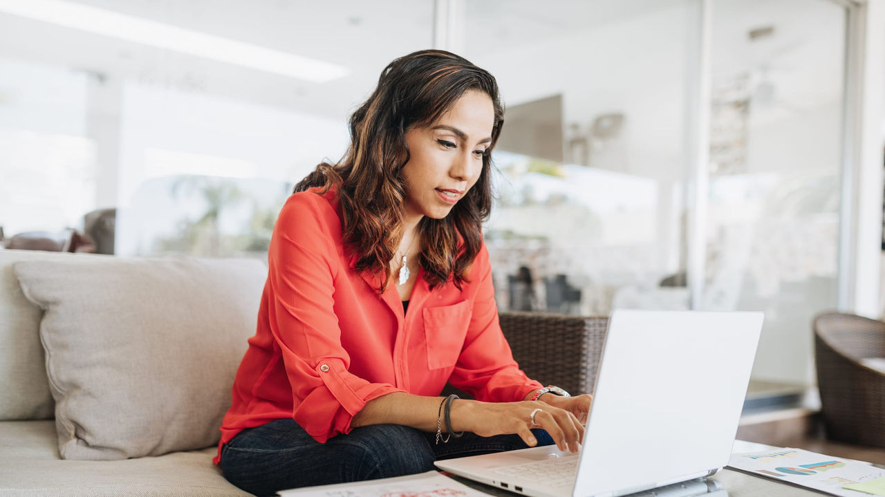 A woman working on a laptop in a living room.