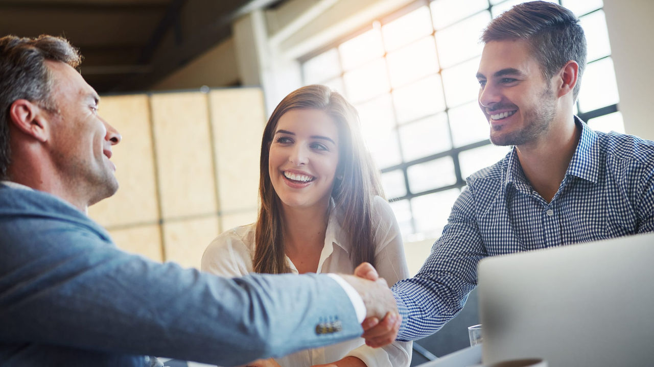 Three business people shaking hands at a meeting.