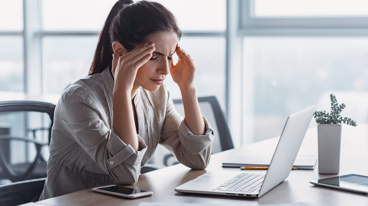 A woman is sitting at a desk with a laptop and papers.