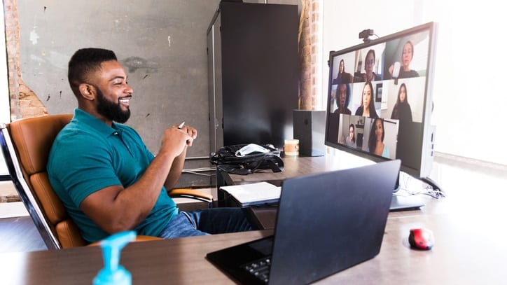 A man sitting at a desk with a laptop and a video camera.