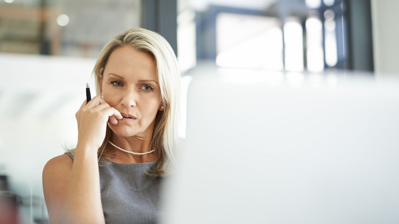 A woman is talking on the phone while sitting in front of a laptop.