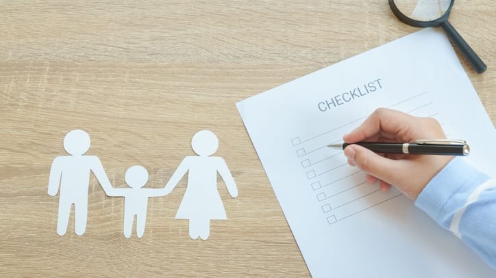 A hand holding a paper with a checklist and a magnifying glass.
