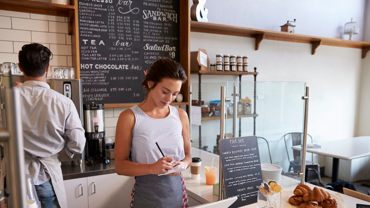 A woman working at the counter of a coffee shop.