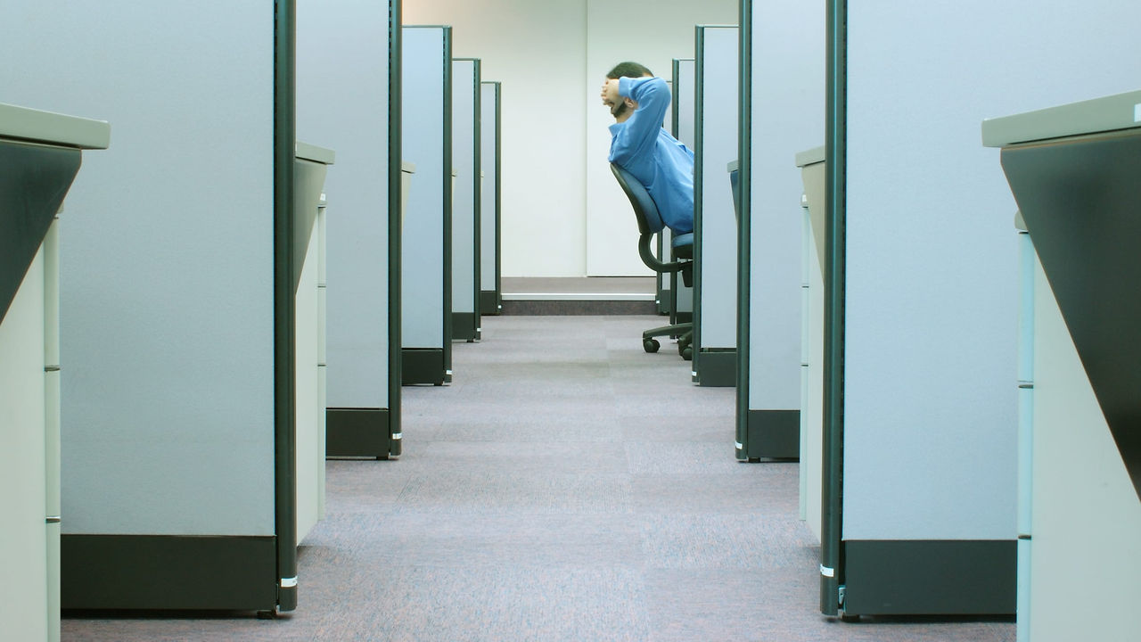 A person is sitting in a cubicle.