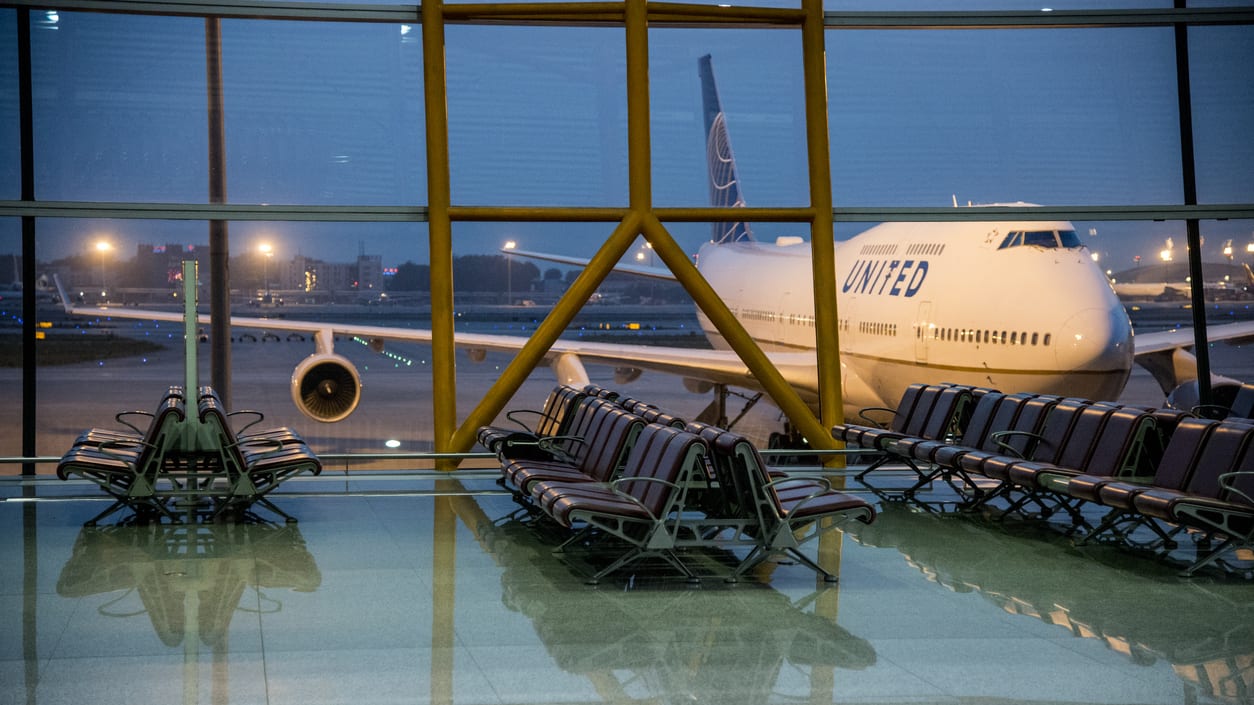 An empty airport waiting room with a plane in the background.
