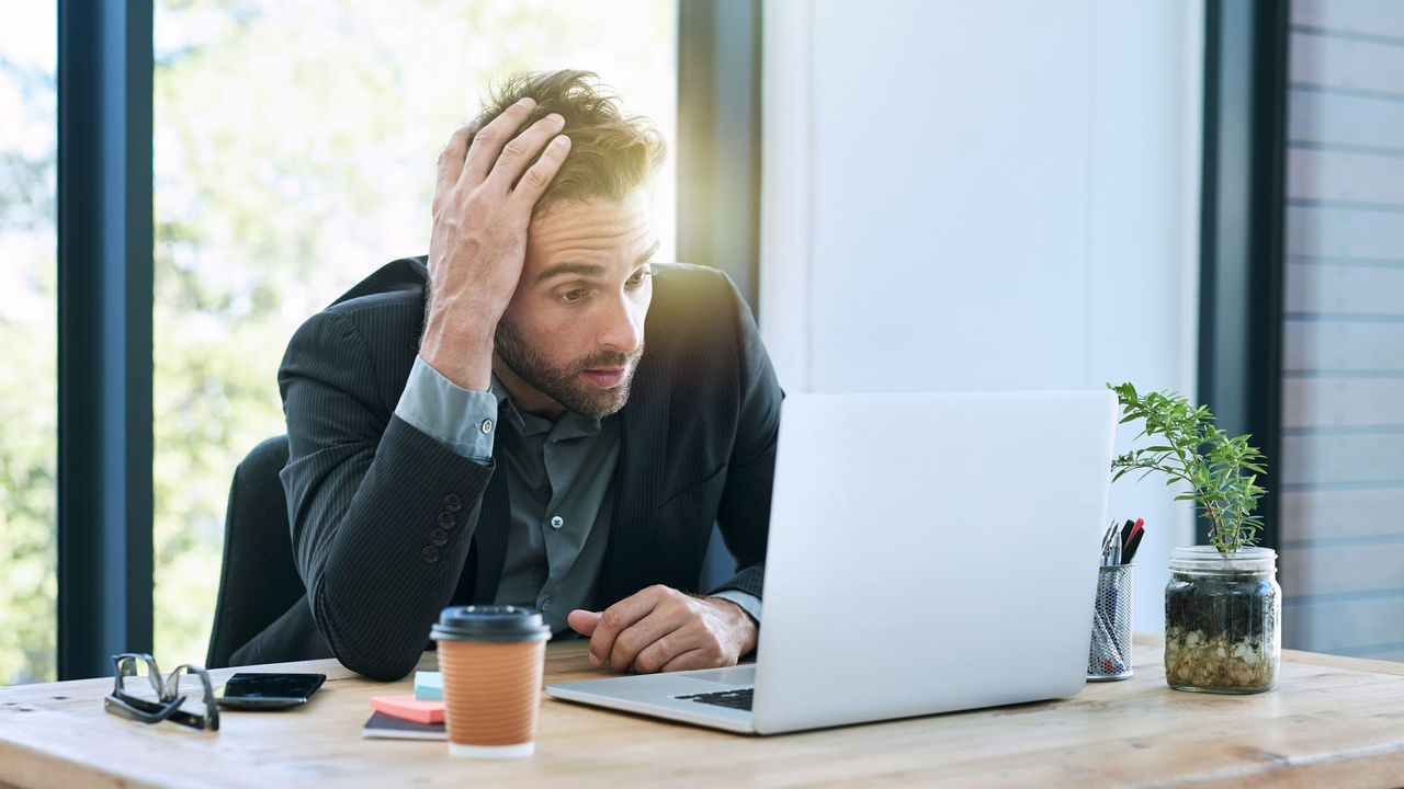 A businessman sitting at a desk with his head on his head.