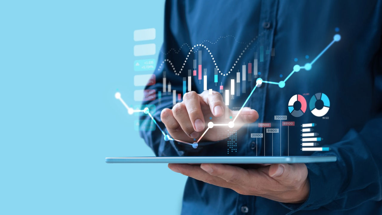 A man is holding a tablet with graphs on it.